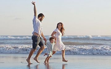 Familie rennt und hüpft am Strand und Meer