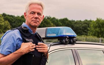 Polizeibeamte stehen vor einem Dienstfahrzeug